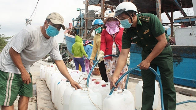 Bộ đội Biên phòng hỗ trợ người dân lấy nước sinh hoạt từ tàu vào can.