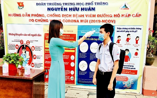  Học sinh Trường THPT Nguyễn Hữu Huân được đo thân nhiệt ngay tại cổng trường.