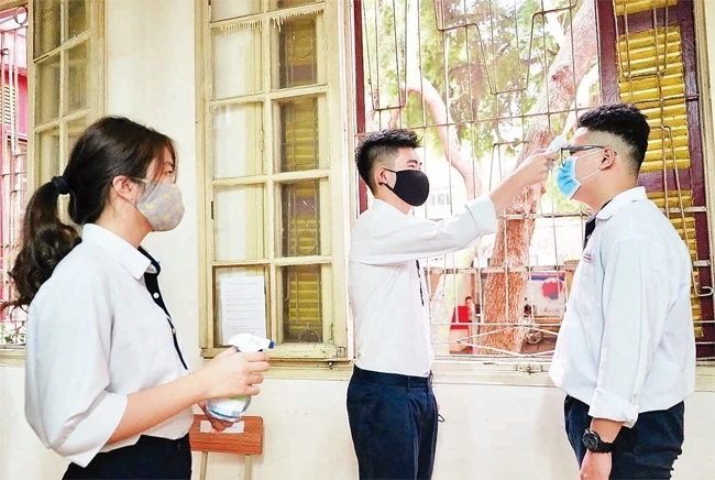 Học sinh Trường THPT Trần Phú (Hoàn Kiếm) kiểm tra thân nhiệt trước khi vào lớp. Ảnh: MINH HÀ