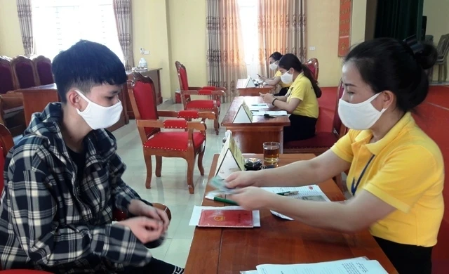 Nhân viên bưu điện cấp phát tiền cho người nghèo ở xã Đông Vinh, thành phố Thanh Hóa.