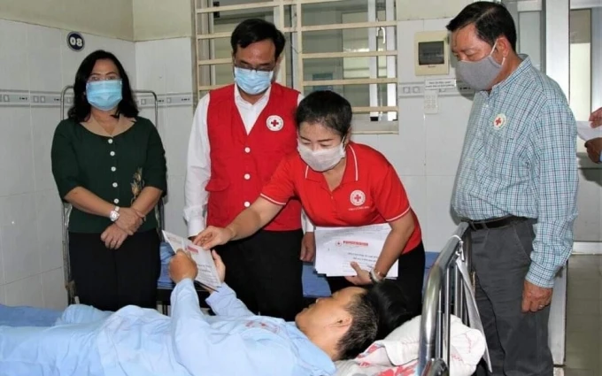 Đại diện Hội Chữ thập đỏ tỉnh Đồng Nai trao tiền hỗ trợ cho nạn nhân bị thương, đang điều trị tại bệnh viện.