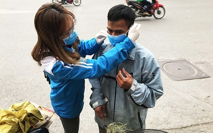 Nữ tình nguyện viên Thủ đô đeo khẩu trang tặng một người nhặt ve chai, trong thời gian cao điểm dịch Covid-19 vừa qua.