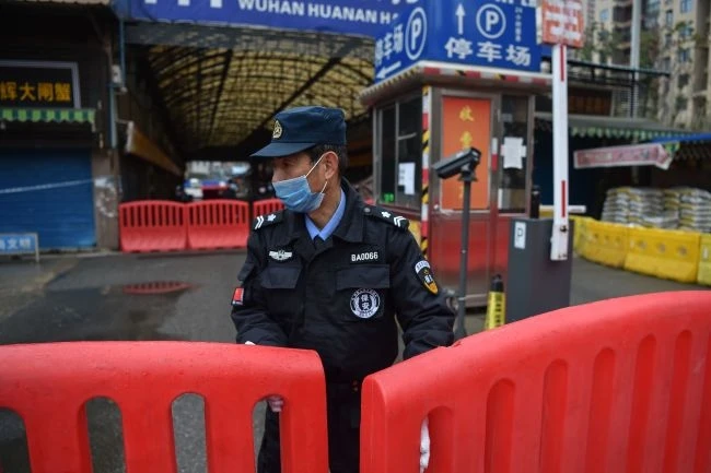 Một sĩ quan cảnh sát đứng canh gác bên ngoài chợ bán buôn hải sản Huanan ngày 24-1, nơi một số báo cáo cho thấy đại dịch bắt đầu. Ảnh: Getty Images.