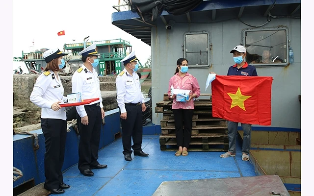 Đại diện Bộ Tư lệnh Vùng 1 (Quân chủng Hải quân) trao vật tư y tế và cờ Tổ quốc tặng ngư dân tại cảng cá Mắt Rồng (huyện Thủy Nguyên).