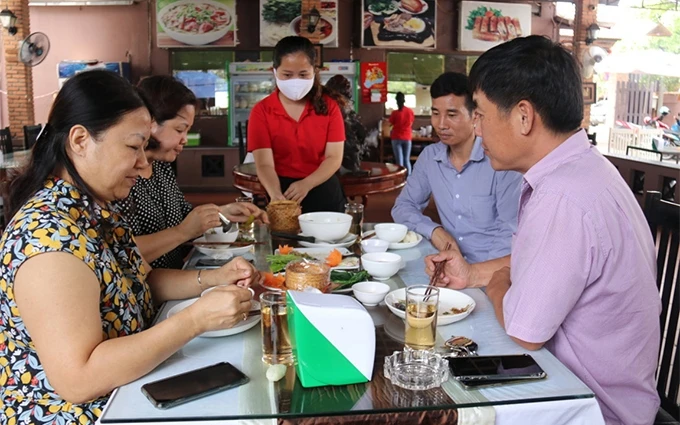 Hôm nay, các cửa hàng ăn uống, dịch vụ xã hội, cơ sở giáo dục, tại Lào đã dần trở lại hoạt động bình thường. Trong ảnh, thực khách tại một nhà hàng ăn uống, ngày 2-6.