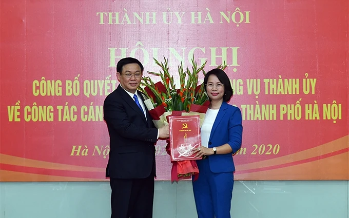 Đồng chí Vương Đình Huệ, Ủy viên Bộ Chính trị, Bí thư Thành ủy Hà Nội trao quyết định và tặng hoa chúc mừng đồng chí Bùi Huyền Mai.