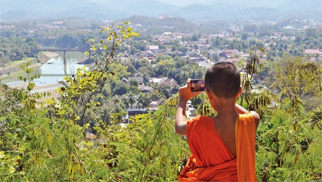 Một chú tiểu chụp ảnh từ trên đỉnh núi Phousi - đỉnh cao nhất Luang Prabang.