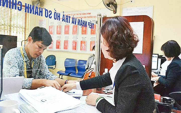 Công chức bộ phận một cửa UBND phường Nguyễn Du (quận Hai Bà Trưng) hướng dẫn công dân thực hiện thủ tục hành chính. Ảnh: LINH CHI