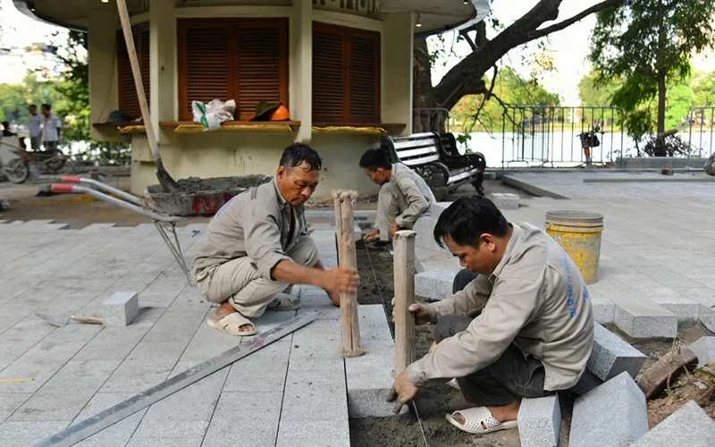 Công nhân lát đá vỉa hè tại khu vực chung quanh hồ Hoàn Kiếm. (Ảnh: THỦY NGUYÊN)