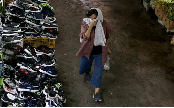 Người phụ nữ dùng khăn che mũi và miệng khi đi trong một khu chợ tại Tehran, Iran, ngày 8-7. (Ảnh: WANA)
