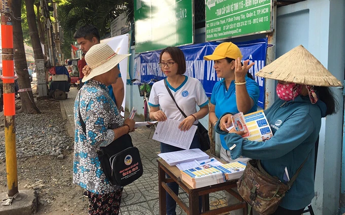 Cán bộ bảo hiểm xã hội TP Hồ Chí Minh tuyên truyền chính sách về BHYT, BHXH cho người dân.