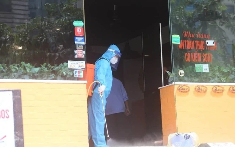 Đội phản ứng nhanh của Trung tâm y tế quận Cầu Giấy phun khử khuẩn tại quán pizza 106 Trần Thái Tông, nơi bệnh nhân N.T.H làm việc. (Ảnh: NAM TIẾN)