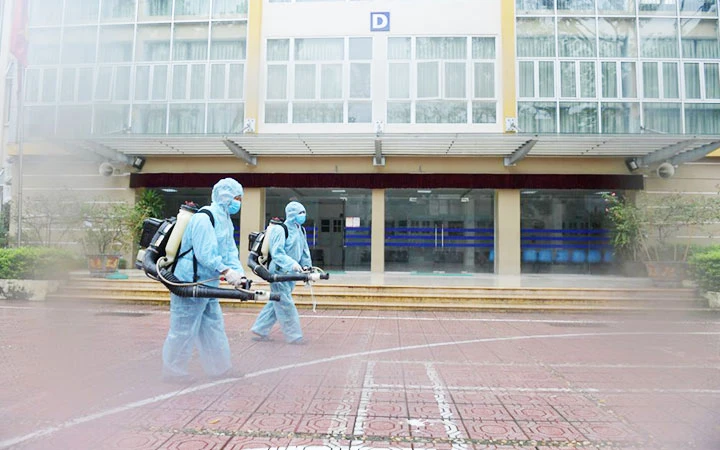 Nhân viên y tế phun thuốc khử khuẩn tại điểm thi Trường THPT Kim Liên (Hà Nội) sáng 6-8. Ảnh: PHẠM HÙNG