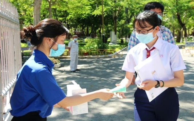 Thanh niên tình nguyện phát khẩu trang cho thí sinh ngay tại cổng vào các điểm thi.