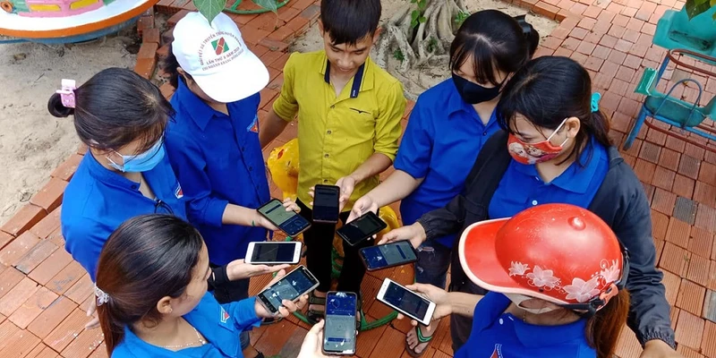 Thanh niên tình nguyện và người dân cùng cài đặt ứng dụng Bluezone ở Gia Lai.