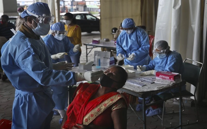 Nhân viên y tế làm xét nghiệm kháng nguyên Covid-19 cho lao động nhập cư tại New Delhi, Ấn Độ, ngày 18-8. (Ảnh: AP)