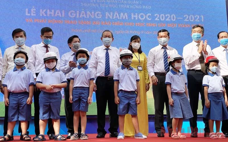 Phó Thủ tướng Trương Hòa Bình cùng các đại biểu trao tặng mũ bảo hiểm cho các em học sinh lớp Một tại trường Tiểu học Trần Hưng Đạo, quận 1, TP Hồ Chí Minh. (Ảnh: QUÝ HIỀN)