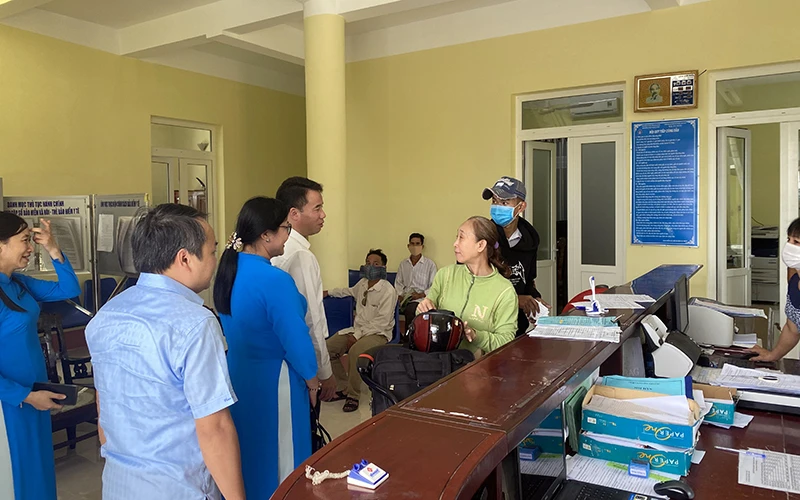 Các đồng chí lãnh đạo Bảo hiểm xã hội Việt Nam trao đổi với người dân đang làm thủ tục tại Bộ phận "một cửa" Bảo hiểm xã hội huyện Vị Thủy (Hậu Giang).