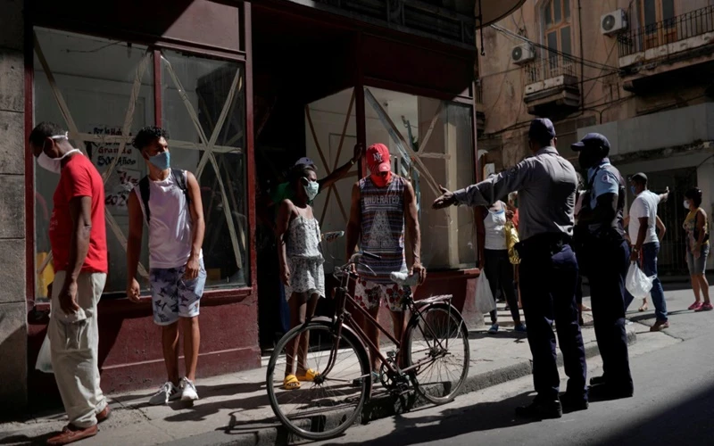 Cảnh sát hướng dẫn người dân tại Havana, Cuba, xếp hàng để mua thực phẩm. (Ảnh: Reuters)