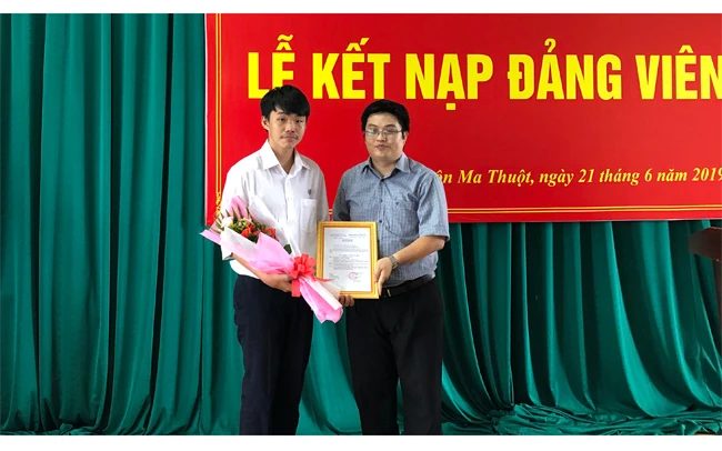 Đồng chí Phạm Công Tuấn (bên phải), Bí thư Chi bộ 2 Trường THPT chuyên Nguyễn Du trao quyết định cho đảng viên mới được kết nạp.