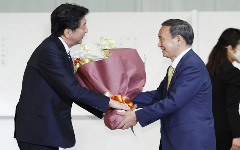 Ông Yoshihide Suga tặng hoa cho ông Shinzo Abe sau khi ông được bầu làm Chủ tịch LDP thay ông Abe, ngày 14-9. (Ảnh: Kyodo)