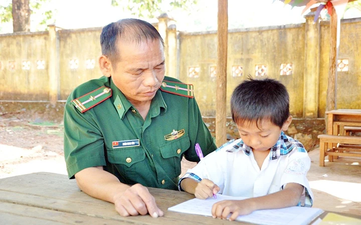 Cán bộ Đồn Biên phòng Thanh Hòa hướng dẫn trẻ học bài.