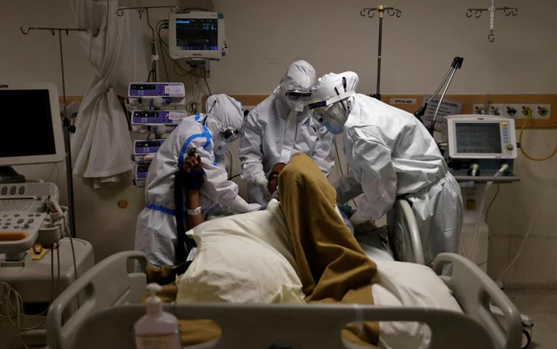 Các nhân viên y tế mặc đồ bảo hộ đang chăm sóc một bệnh nhân Covid-19 trong bệnh viện tại Ấn Độ. Ảnh: Reuters