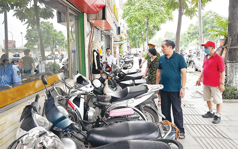 Cán bộ Tổ dân phố 17 phường Khương Mai, quận Thanh Xuân tuyên truyền, nhắc nhở hộ kinh doanh không lấn chiếm vỉa hè, lòng đường. Ảnh: Ðăng Anh 