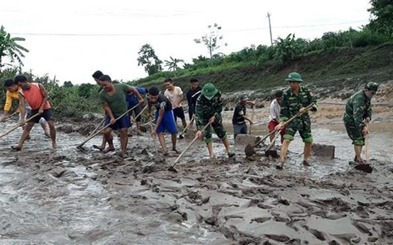 Bộ đội Biên phòng tỉnh Quảng Trị giúp người dân các xã miền núi huyện Hướng Hóa thu dọn bùn đất bồi lấp trên tuyến giao thông do bão số 5 gây ra. Ảnh: HỒ CẦU 
