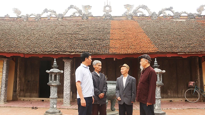 Ông Đễ (bên phải) kể sự tích chợ Mới ông già cùng các bậc cao niên trong làng và trưởng thôn ở đình làng Vân La.