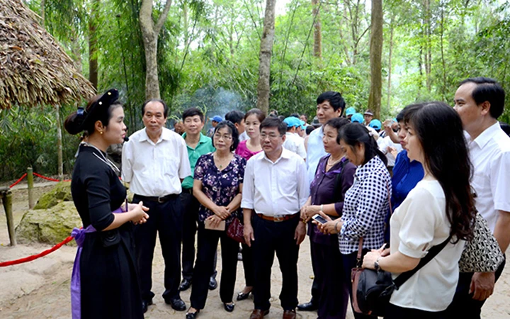 Hướng dẫn viên Khu du lịch lịch sử, văn hóa và sinh thái Tân Trào (Tuyên Quang) và du khách tại Lán Nà Nưa. Ảnh: thu trang