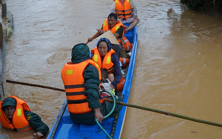 Lực lượng chức năng huyện Cam Lộ (Quảng Trị) đưa người già, trẻ em ra khỏi vùng ngập lũ.
