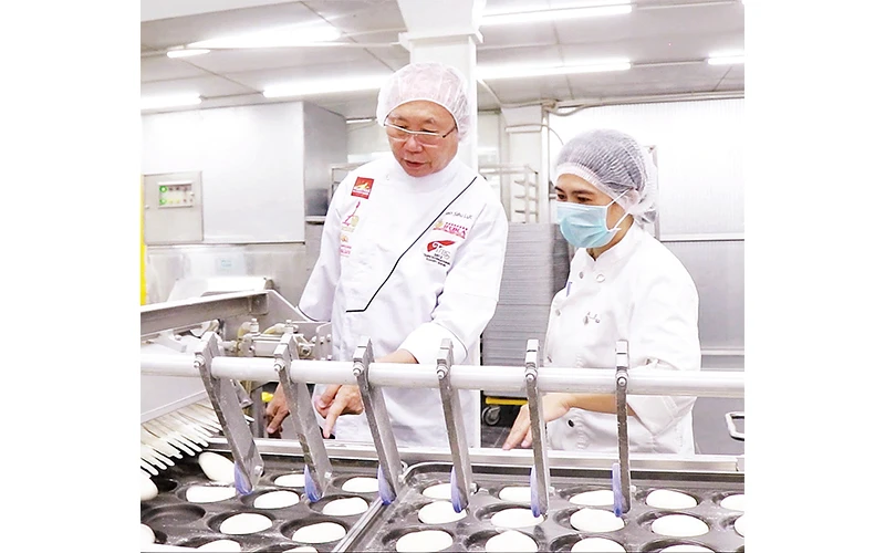 Ông Kao Siêu Lực (bên trái) kiểm tra dây chuyền sản xuất bánh mì.