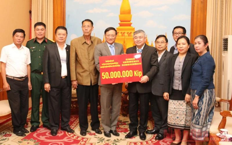 Đại sứ Việt Nam tại Lào Nguyễn Bá Hùng (thứ 5 từ trái qua) trao số tiền ủng hộ Lào, chiều 26-10.