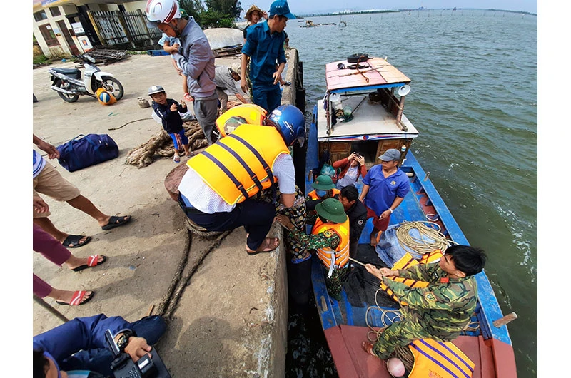 Lực lượng chức năng giúp người dân xã Tam Hải (huyện Núi Thành) đi tránh bão.
