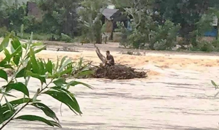 Ông Nguyễn Văn Tự đang mắc kẹt giữa dòng nước chờ cứu hộ. 