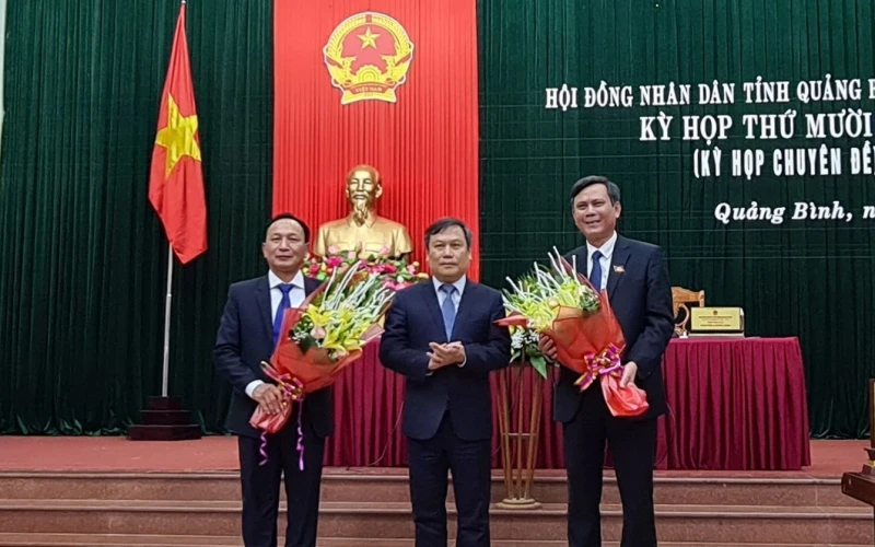 Ông Trần Hải Châu (trái) và ông Trần Thắng (phải) nhận hoa chúc mừng của Bí thư Tỉnh ủy Quảng Bình Vũ Đại Thắng.