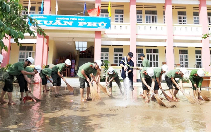 Cán bộ, chiến sĩ Công an tỉnh Phú Yên quét dọn bùn đất sau khi nước lũ rút tại Trường tiểu học Xuân Phú. Ảnh: BỘ CÔNG AN