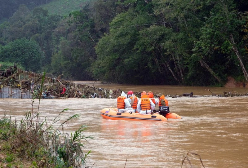 Lực lượng cứu hộ triển khai tìm kiếm nạn nhân mất tích tại khu vực cầu treo bị lũ cuốn.