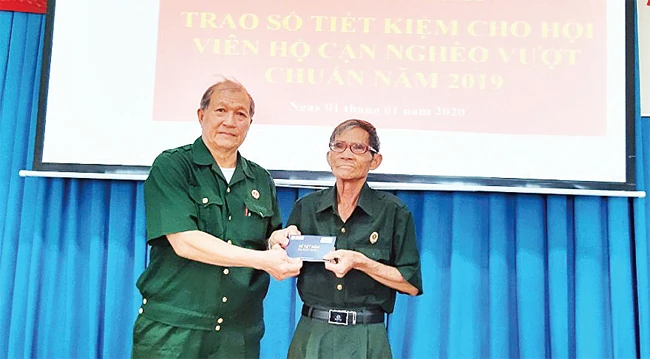 Chủ tịch Hội Cựu chiến binh phường 15 (quận Bình Thạnh) Huỳnh Đăng Bửu (bên trái) trao sổ tiết kiệm tặng hội viên hộ cận nghèo vượt chuẩn.