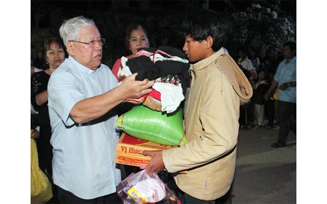 Linh mục Đinh Ngọc Lễ tặng quà người nghèo trong một hoạt động từ thiện của Ủy ban Đoàn kết Công giáo Việt Nam TP Hồ Chí Minh. Ảnh: HOÀNG TUẤN