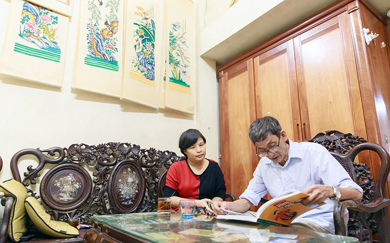 Chị Nguyễn Thị Thu Hòa trao đổi với nghệ nhân Lê Ðình Nghiên về tranh dân gian Hàng Trống. 