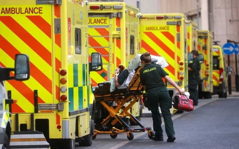 Nhân viên y tế của Anh đưa người bệnh lên xe cứu thương để tới bệnh viện tại London. (Ảnh: Reuters)