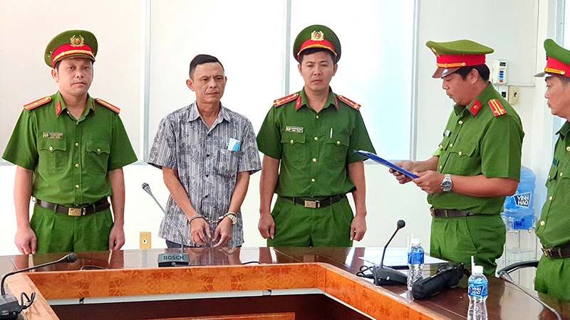 Cơ quan Cảnh sát điều tra Công an tỉnh Bình Thuận đọc Quyết định khởi tố bị can, Lệnh bắt tạm giam đối với Trần Văn Đông (áo sơ mi) tại nơi làm việc.
