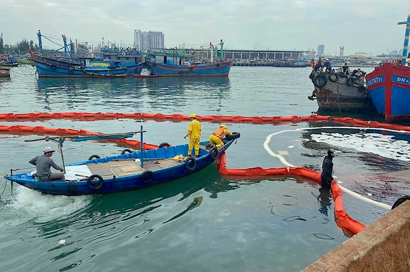 Lực lượng chức năng xử lý vết dầu tràn tại Âu thuyền và Cảng cá Thọ Quang.