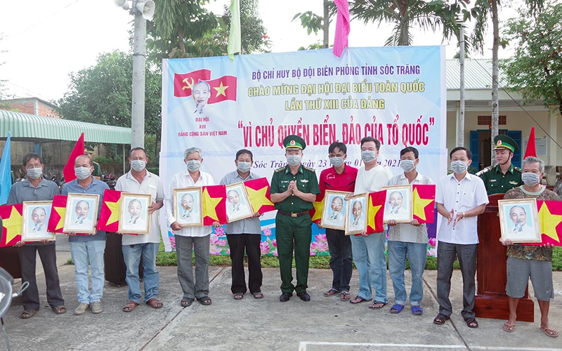 Đại tá Lê Văn Anh, Phó chính uỷ, BĐBP tỉnh trao cờ tổ quốc và ảnh Bác Hồ cho ngư dân.