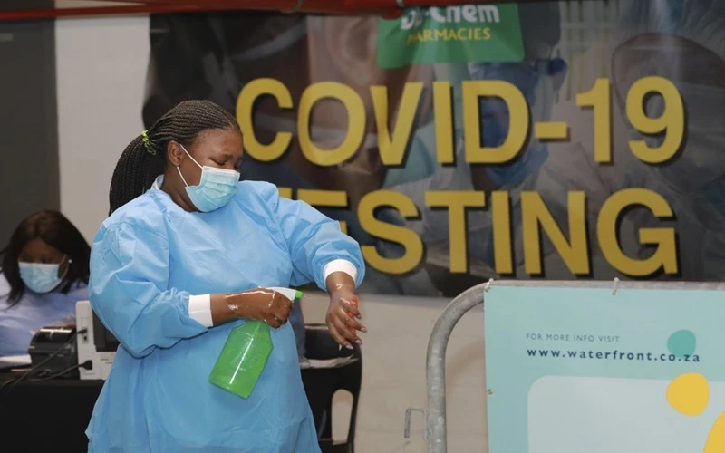 Nhân viên y tế xịt khử trùng tay trước khi làm xét nghiệm cho người dân tại TP Cape Town, Nam Phi, tháng 1-2021. (Ảnh: AP)