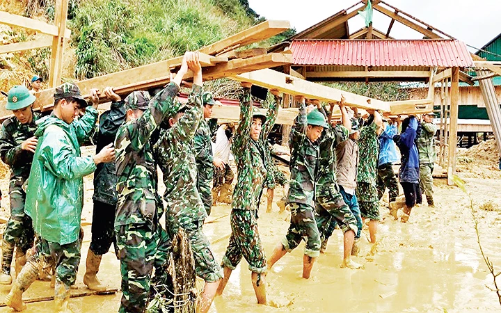 Cán bộ, chiến sĩ Đồn Biên phòng Ga Ry (Bộ Chỉ huy Bộ đội Biên phòng tỉnh Quảng Nam) giúp nhân dân huyện Tây Giang dựng lại nhà sau bão. Ảnh: PHAN TIẾN DŨNG