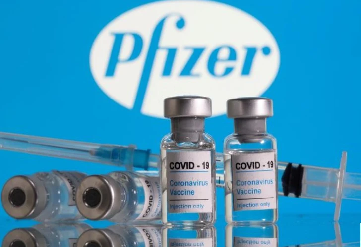 Lọ vaccine ngừa Covid-19 đặt trước logo Pfizer được chụp vào ngày 9-2. Ảnh: Reuters.
