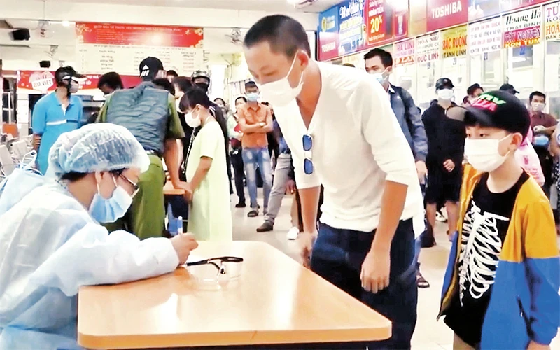 Nhân viên y tế lấy mẫu xét nghiệm đối với những người từ các địa phương có dịch Covid-19 đến TP Hồ Chí Minh sau đợt nghỉ Tết Nguyên đán Tân Sửu 2021 tại sân bay Tân Sơn Nhất. ảnh: HCDC